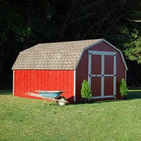 value gambrel barn with 4 foot sidewalls lifestyle picture with wheelbarrow beside it